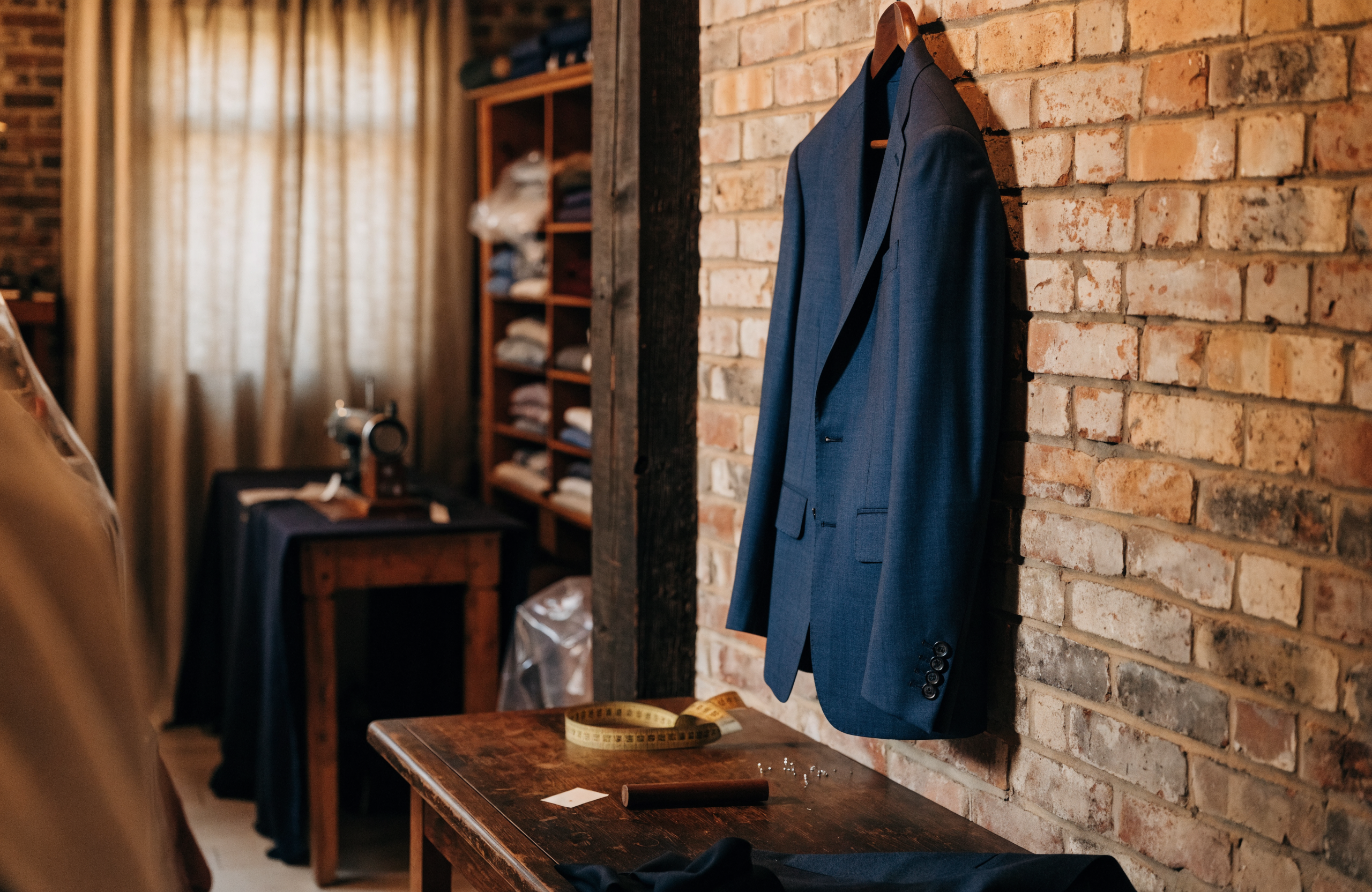 Illustrative image of a bespoke menswear boutique with a navy wedding suit jacket on a hanger
