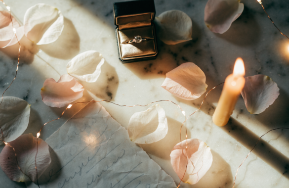Illustrative romantic proposal flatlay with ring box, rose petals and candlelight