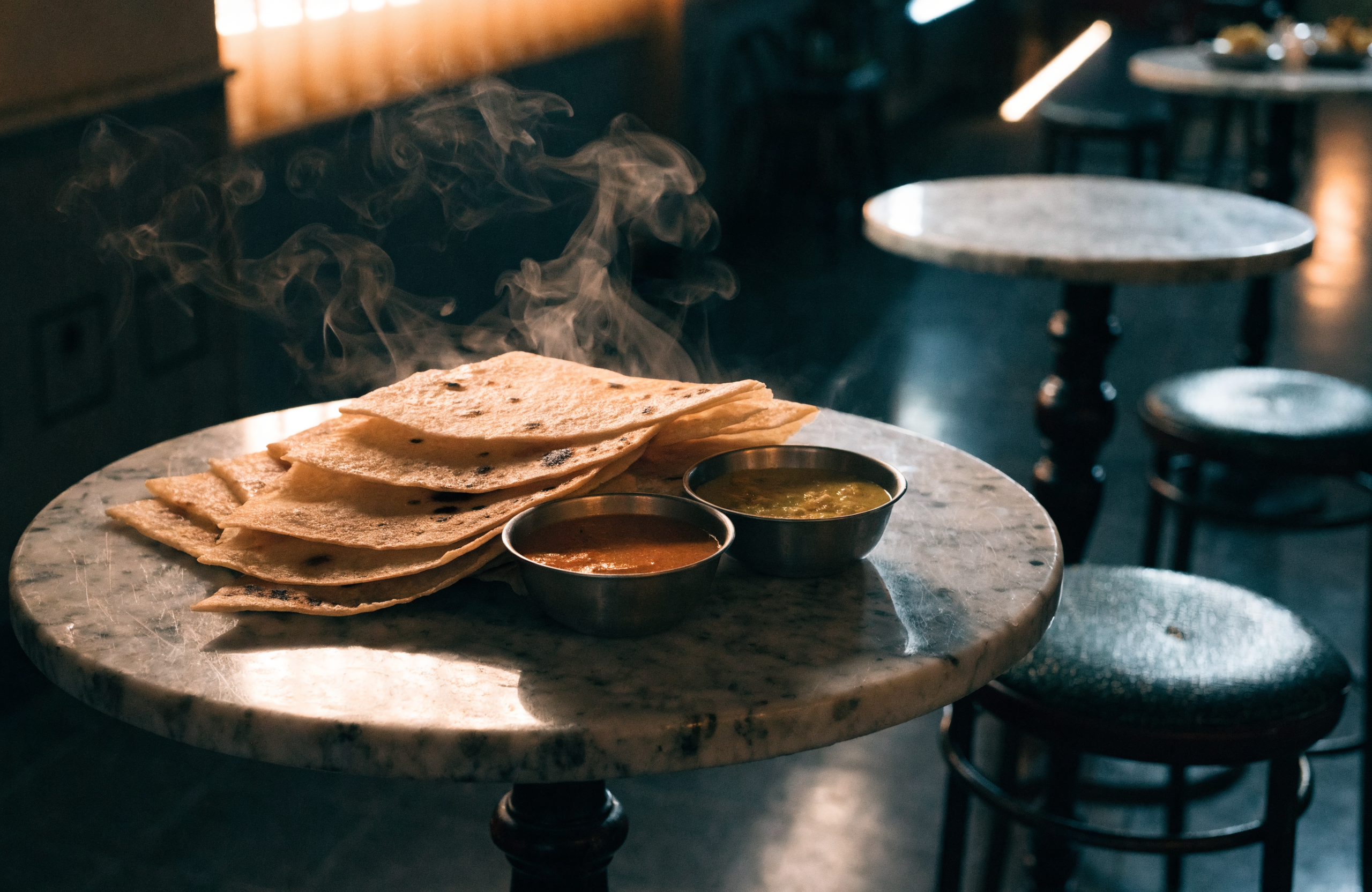 Illustrative image of prata and curry bowls on a coffeeshop table at night