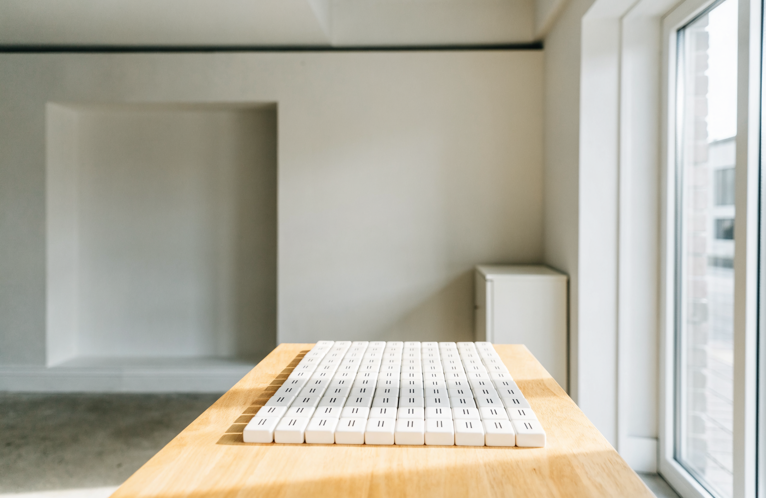 Illustrative image of a bright minimalist studio with mahjong tiles arranged on a table, representing Tile And Flow mahjong experiences in Singapore